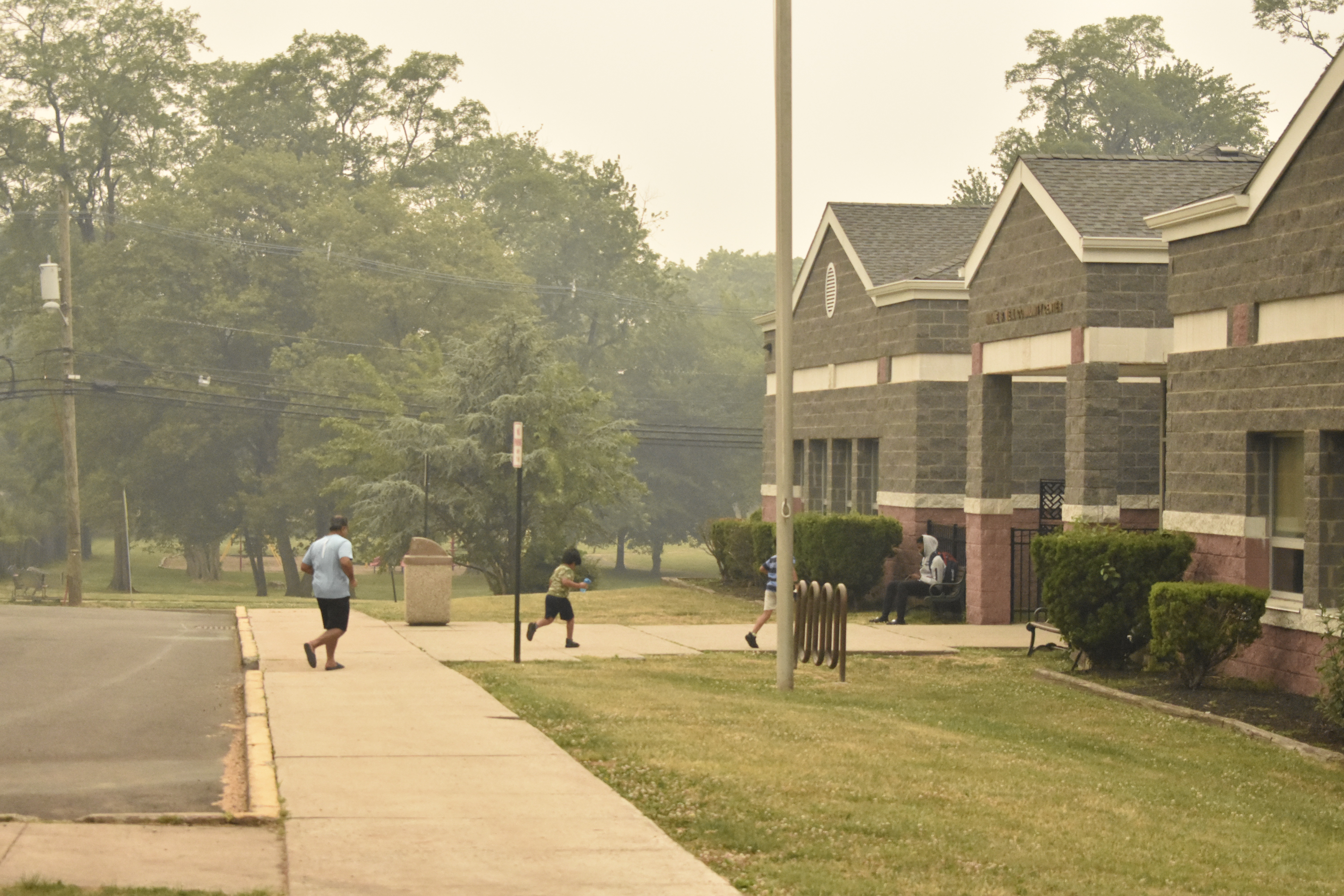 An adult and two children run inside the Minnie B. Veal Community Center in the midst of the smoke haze at 17:08 EDT 2023-06-07. ZFJ/Alvin Wu